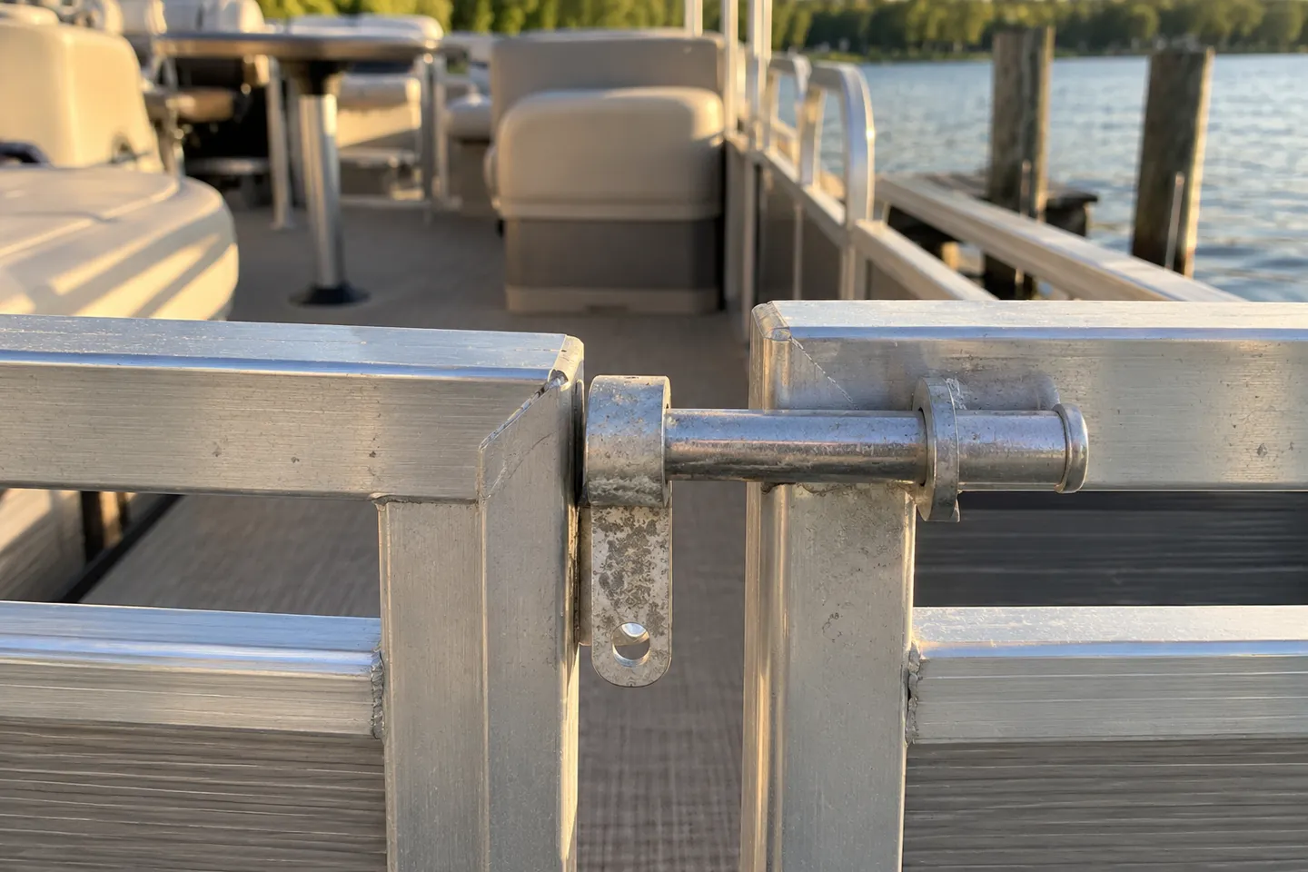 A pontoon boat fence gate held shut by its bare aluminum rod-and-tab latch, photographed close up from the dock side.